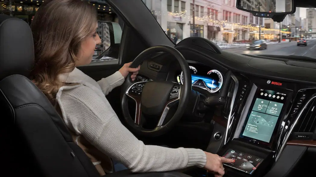 Close up interior view of caucasian woman driving car using Bosch touchscreen